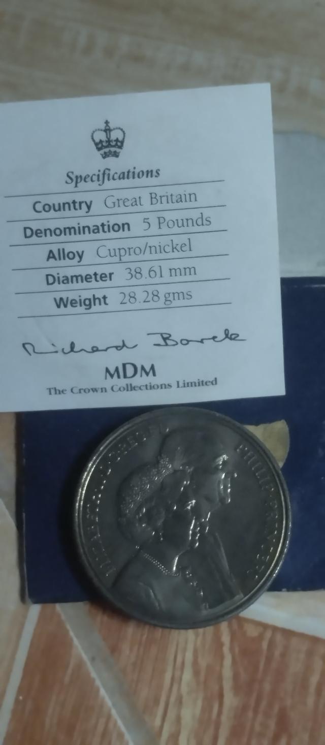 เหรียญในภาพคือเหรียญกษาปณ์ที่ระลึก 5 ปอนด์ของสหราชอาณาจักร (United Kingdom £5 commemorative coin) ที่ออกในปี 1997 เพื่อเฉลิมฉลองครบรอบ 50 ปีวันอภิเษกส รูปที่ 2