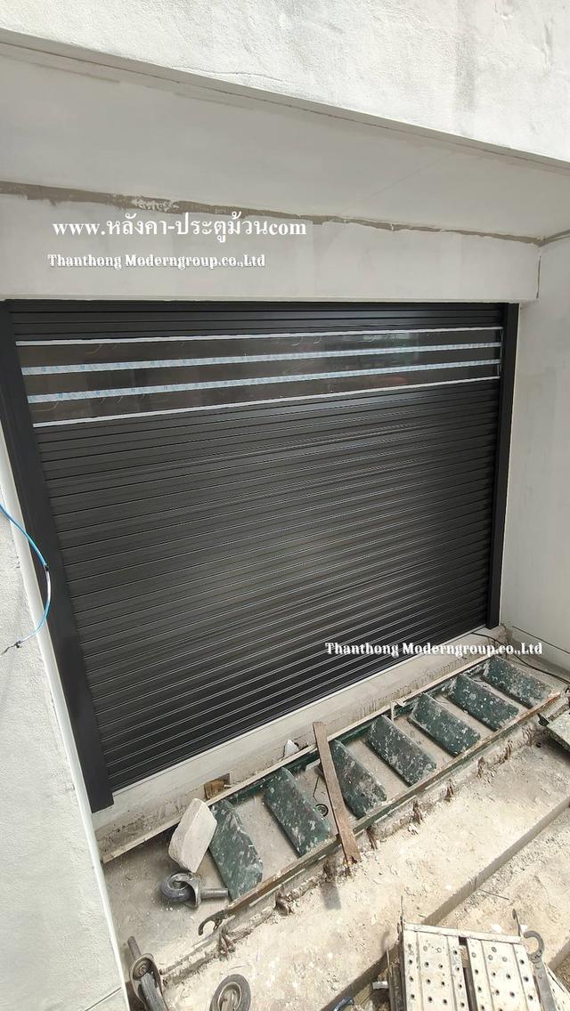 หน้างานนี้เลือกใช้ ประตูม้วนระบบมอเตอร์ สี Metallic Charcoal (เทาดำเมทัลลิก) สีสวยหรู ทันสมัย ช่วยยกระดับความพรีเมียมให้ตัวบ้าน