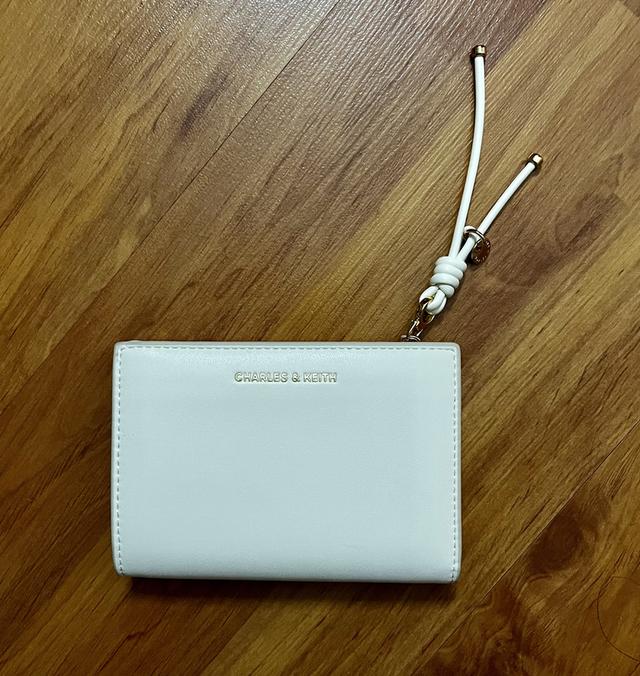 กระเป๋าสตางค์ CHARLES & KEITH ใบสั้นพับสองทบ โดดเด่นด้วยดีเทล สายดึงซิปผูกปม (Knot Charm) พร้อมช่องใส่บัตร และช่องซิปใส่เหรียญ ราคาช็อปไทย: 1,590 บาท