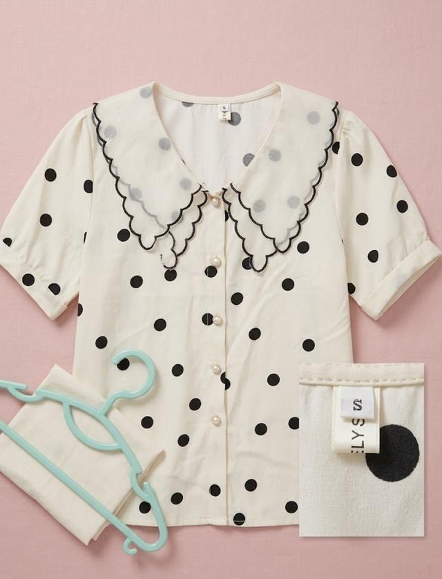 เสื้อเชิ้ตแขนสั้นสีครีมลายจุดสีดำ ตกแต่งด้วยปกคอปีเตอร์แพน (Peter Pan collar) สีขาวโปร่งขอบหยักสีดำ