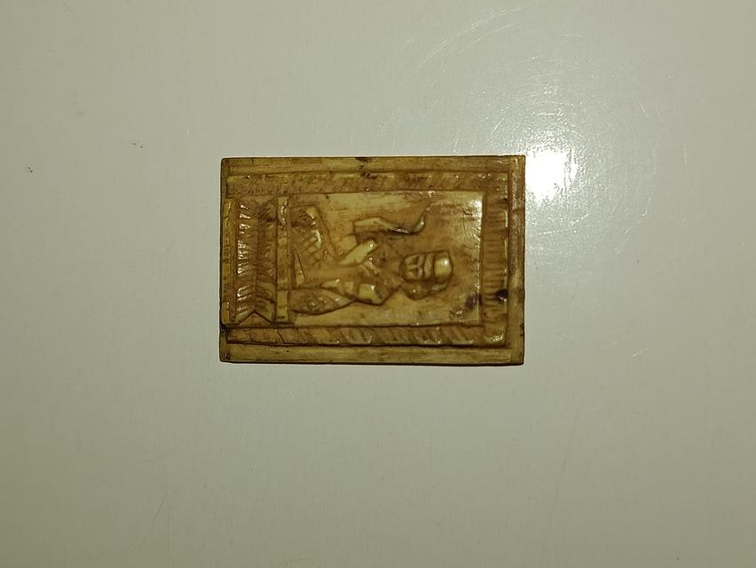 พระเครื่องหรืองาแกะโบราณ ซึ่งเป็นเครื่องรางของขลังที่ได้รับความนิยมในประเทศไทย  วัตถุนี้มีพื้นผิวสีเหลืองนวลและมีรอยขีดข่วนจำนวนมาก ซึ่งเป็นลักษณะของง