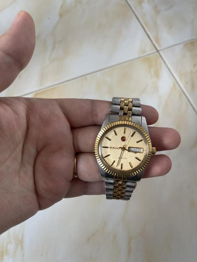 RADO ตัวเรือน: สแตนเลสสตีลขอบ: ขอบฟันปลา สีทองสาย: สแตนเลส สีเงินสลับทอง หน้าปัด: สีทองโลโก้: สมอแดง กระจก: Sapphire Crystal