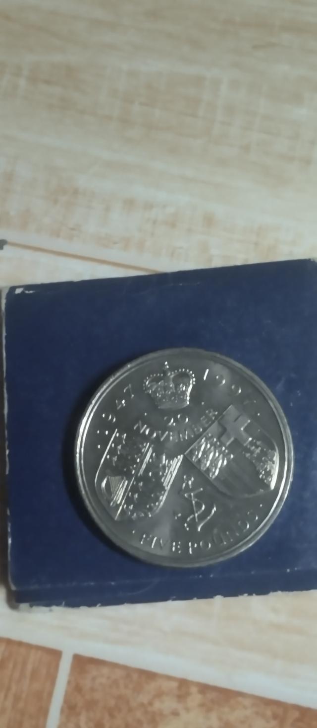 เหรียญในภาพคือเหรียญกษาปณ์ที่ระลึก 5 ปอนด์ของสหราชอาณาจักร (United Kingdom £5 commemorative coin) ที่ออกในปี 1997 เพื่อเฉลิมฉลองครบรอบ 50 ปีวันอภิเษกส