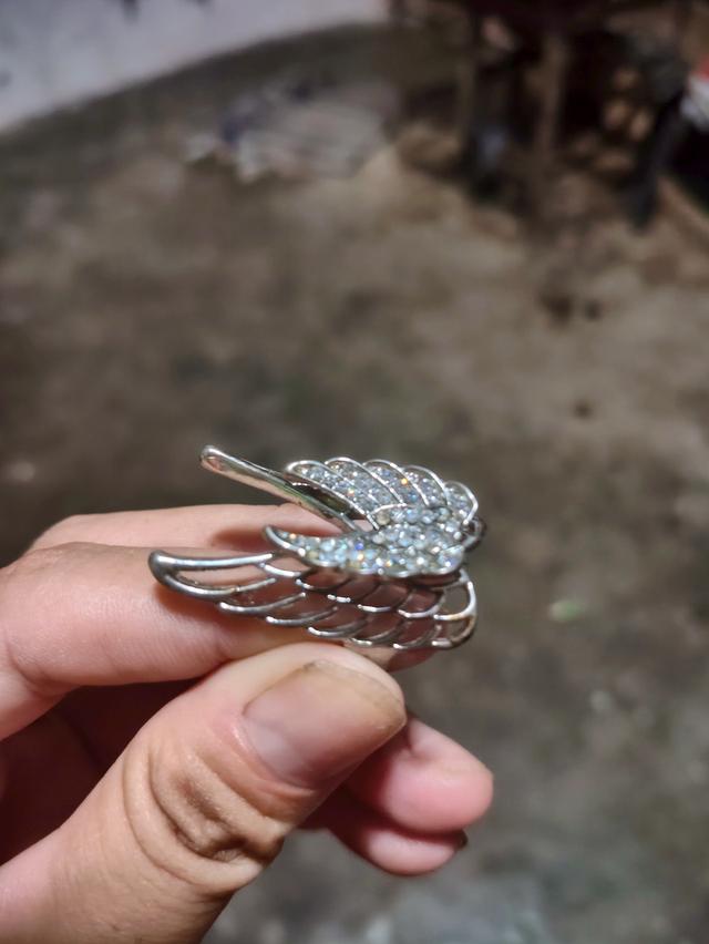 ตัวเรือนเป็นโลหะสีเงินชุบตกแต่งด้วยคริสตัลหรือเพชรรัสเซีย (Cubic Zirconia) ขนาดเล็กบนตัวปีกดีไซน์ปีกคู่ซ้อนกันในลักษณะโอบรอบนิ้วมือ