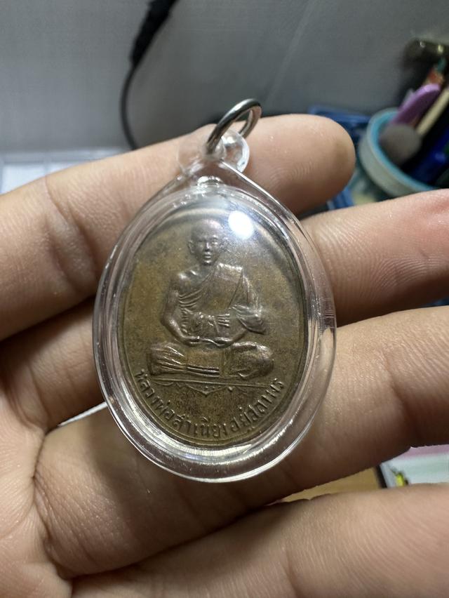 เหรียญรุ่นแรก (เหรียญรูปไข่หน้าเณร) หลวงพ่อสำเนียง อยู่สถาพร วัดเวฬุวนาราม จังหวัดนครปฐม สร้างขึ้นประมาณปี พ.ศ. 2493