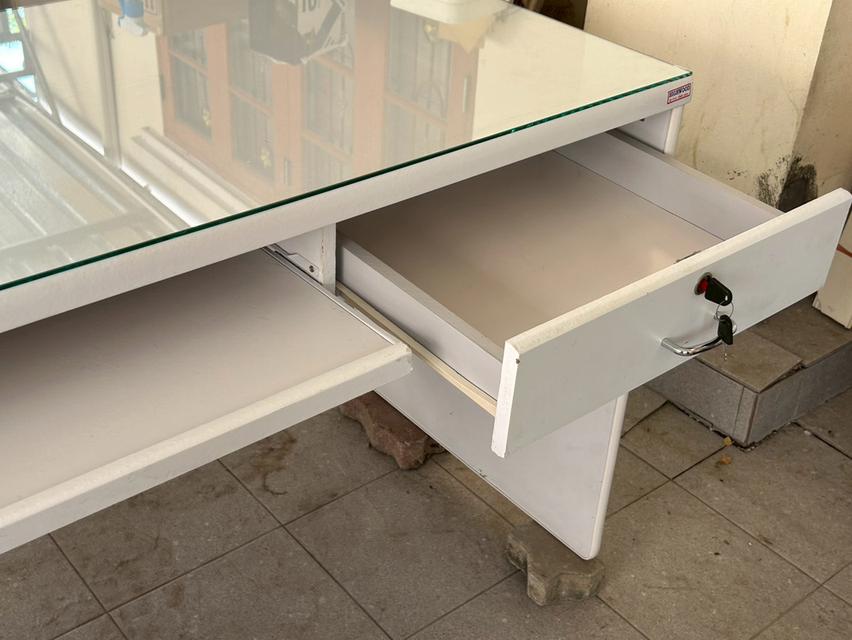โต๊ะทำงานสีขาว ราคา 1,200 บาท ก120xล60xส75 ซม. กระจกปูโต๊ะ 4 มม.ลบมุมเรียบ เก๊ะด้านขวามีลูกกุญแจล็อคได้ เก๊ะกลางรางเลื่อน ด้านหน้าโต๊ะเว้นระยะหัวเข่า